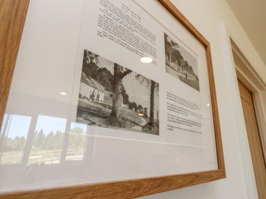 A framed picture with black and white images and text hanging on a white wall with a wooden door nearby at Barolo in Seaview