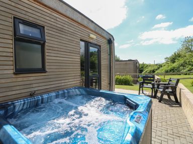 An outdoor area with a blue hot tub next to a wooden building and two black chairs on a paved patio at Barolo in Seaview