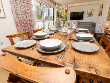 A wooden dining table set with plates, bowls, wine glasses, and cutlery with chairs around it in a dining room at Cava in Seaview