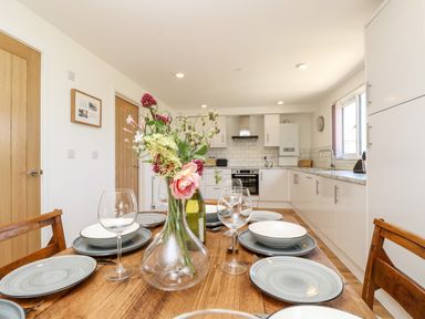 A kitchen and dining table with plates glasses and flowers in a vase at Cava in Seaview