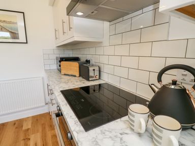 A kitchen countertop with a black electric kettle two striped mugs a toaster a microwave and a cutting board with white tiled backsplash at Cava in Seaview