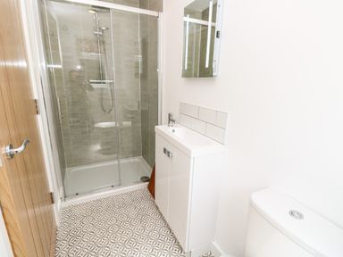 A bathroom with a shower enclosure a white sink cabinet and a toilet at Cava in Seaview