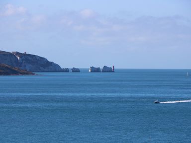 A coastal view with sea cliffs and rock formations in the water with a small boat moving in the sea at Chianti in Seaview