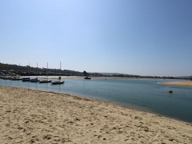 A sandy beach with boats anchored near the shore on a calm body of water at Chianti in Seaview