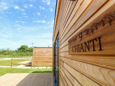 The exterior of a wooden cabin with a sign reading Chianti and a view of another wooden cabin in a grassy area at Chianti in Seaview