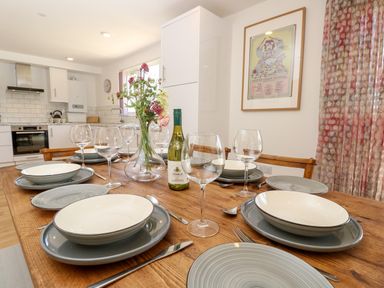 A dining table set with plates bowls glasses cutlery a wine bottle and flowers in a kitchen at Chianti in Seaview
