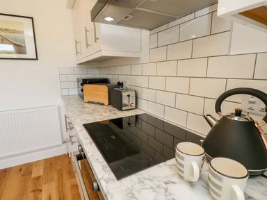 A kitchen countertop with a kettle two mugs a toaster and a microwave with white tile backsplash at Chianti in Seaview