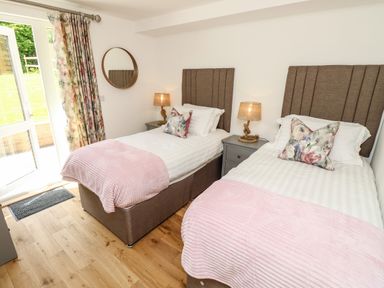 A bedroom with two single beds pink throws and floral cushions at Chianti in Seaview