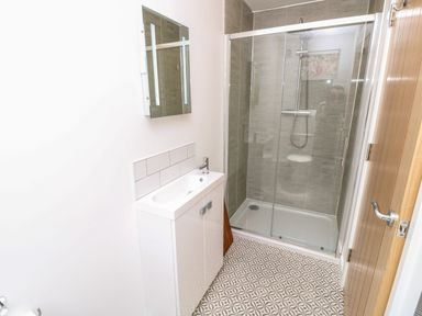 A bathroom with a white sink cabinet a wall-mounted mirror and a glass-enclosed shower at Chianti in Seaview