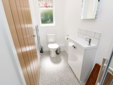 A bathroom with a toilet a sink with cabinet a wooden door and a window at Chianti in Seaview