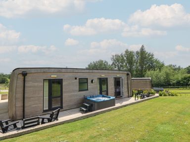 A wooden cabin with hot tub and outdoor seating on a patio surrounded by grass at Chianti in Seaview