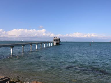 A pier extending over the sea with a circular building at the end and ships in the distance at Claret in Seaview
