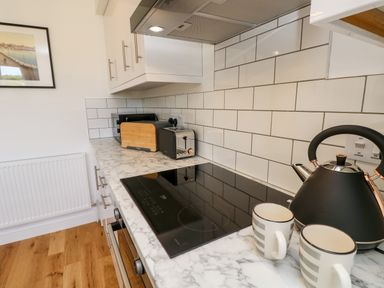 A kitchen countertop with a black kettle two striped mugs toaster and bread bin with white subway tile backsplash at Claret in Seaview