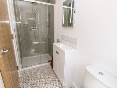 A small bathroom with a glass shower enclosure a white sink cabinet a wall-mounted mirror and a toilet at Claret in Seaview