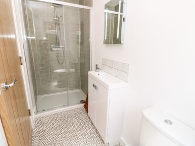 A bathroom with a glass shower enclosure a white vanity with mirror and a toilet at Muscat in Seaview