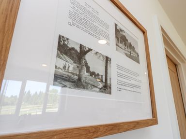 A close-up of a framed black and white historical photograph with text on a wall near a wooden door at Muscat Seaview