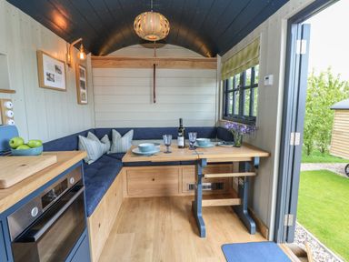 A compact dining area with a wooden table set with plates and glasses in a small cabin at Merlot in Pondwell near Seaview