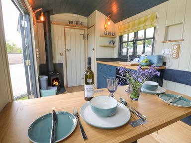 A kitchen and dining area with table settings a bottle of wine and flowers at Merlot in Pondwell near Seaview