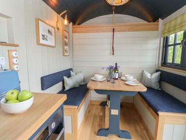 A dining area with a wooden table set for two and blue cushioned bench seating at Malbec Pondwell near Seaview