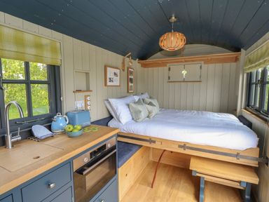 A small room with a bed next to kitchen counters and windows at Malbec Pondwell near Seaview