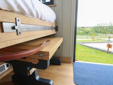 A wooden bed frame with a leather strap and a blue mat on a wooden floor at Malbec Pondwell near Seaview