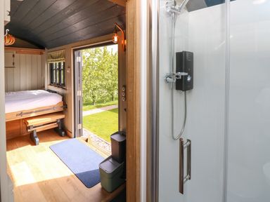 A compact room with a bed and an open door showing outdoor greenery next to a shower in a glass enclosure at Malbec Pondwell near Seaview