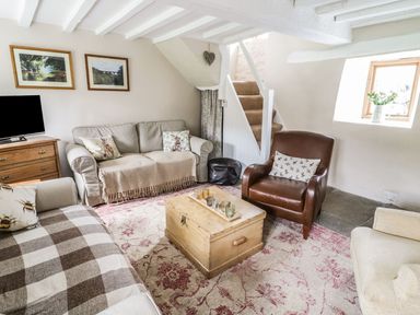 A living room with sofas and armchair around a wooden chest coffee table at Tan Y Garth Cottage in Glyndyfrdwy near Llangollen