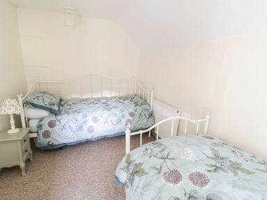 A bedroom with two single beds and a bedside table with a lamp at Tan Y Garth Cottage in Glyndyfrdwy near Llangollen