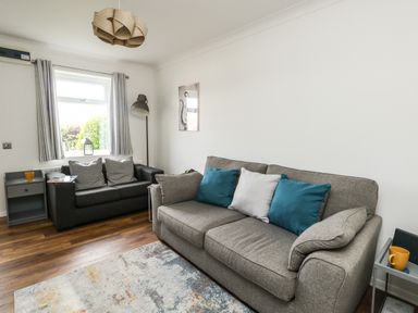 A living room with two sofas and a floor lamp at Little Tern in Brewers Quay Harbour