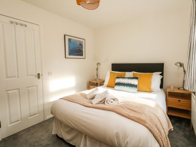 A bedroom with a double bed with cushions and folded towels beside two bedside tables with lamps at Little Tern Brewers Quay Harbour