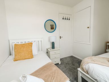A bedroom with two single beds a bedside table with lamp and a round mirror on the wall at Little Tern in Brewers Quay Harbour