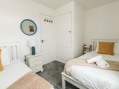A bedroom with two beds a nightstand with a lamp and a mirror on the wall at Little Tern in Brewers Quay Harbour