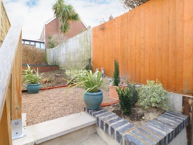 A small garden area with potted plants and a gravel ground next to wooden fences at Little Tern Brewers Quay Harbour