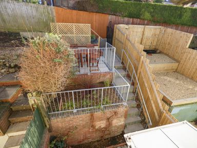 A tiered backyard garden with fenced patio seating area stairs and gravel beds at Little Tern Brewers Quay Harbour