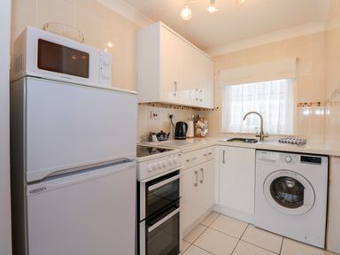 A kitchen with a refrigerator microwave oven stove kettle sink and washing machine at Chalet 12 in Hemsby