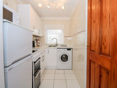 A kitchen with a white refrigerator microwave oven washing machine sink and wooden door at Chalet 12 in Hemsby