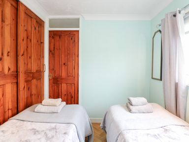 A bedroom with two single beds towels on beds wooden door and closet mirror on wall at Chalet 12 in Hemsby