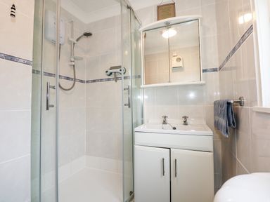A bathroom with a shower enclosure sink with cabinet and mirror at Chalet 12 in Hemsby