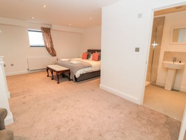 A bedroom with a double bed bench at the foot of the bed and an en suite bathroom at Shepherds House in Lowick