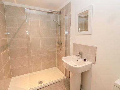 A bathroom with a shower enclosure a sink a mirror and toiletries at Shepherds House in Lowick