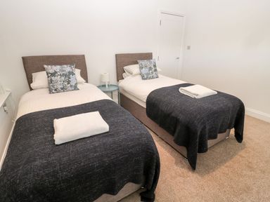 A bedroom with two single beds with dark blankets and floral pillows at Shepherds House in Lowick