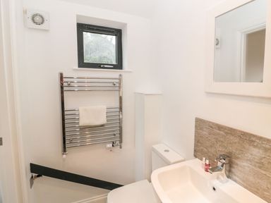 A bathroom with a sink a toilet a towel rail and a window at Shepherds House in Lowick