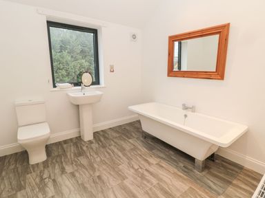 A bathroom with a toilet sink bathtub mirror and window at Shepherds House in Lowick