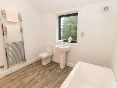 A bathroom with a toilet sink bathtub and towel rack near a window at Shepherds House in Lowick
