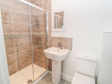 A bathroom with a shower enclosure sink and toilet at Shepherds House in Lowick