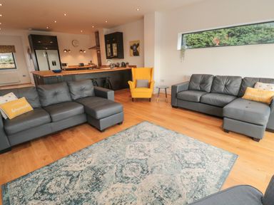 A living room with two gray sofas and a yellow armchair next to an open kitchen at Shepherds House in Lowick