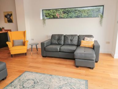 A living room with a gray sofa and yellow armchair near a small side table at Shepherds House in Lowick