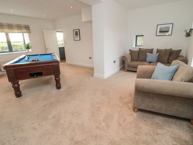 A room with a pool table and two brown sofas with blue cushions at Shepherds House in Lowick