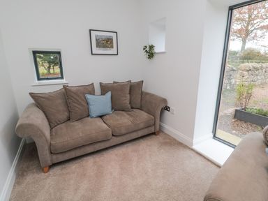 A room with brown sofas and a framed picture on the wall at Shepherds House in Lowick