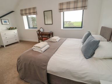 A bedroom with a bed towels on the bed a wooden chair desk dresser with plant and photo frame at Shepherds House in Lowick